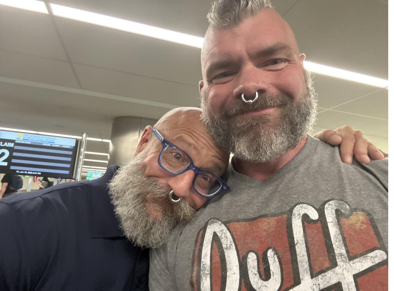 Barclay Barrios embracing a friend at the airport, arm around his shoulder.